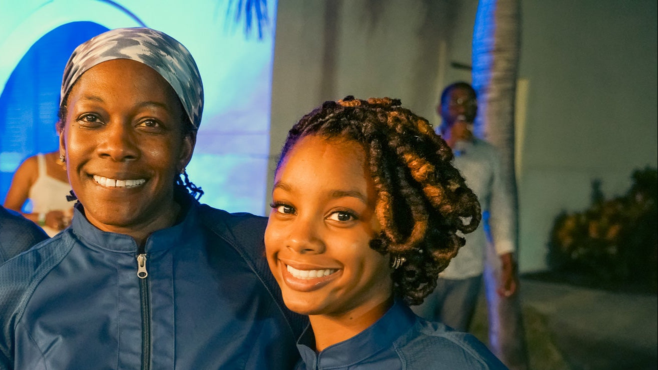 Three people in matching blue jackets standing together in an indoor setting.