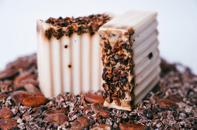 Bar of soap with a textured top on a bed of cocoa beans