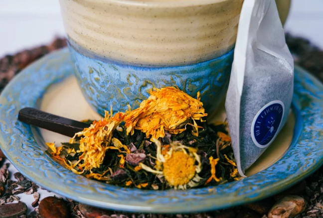 Tea leaves with a tea bag in a blue teacup on a wooden surface