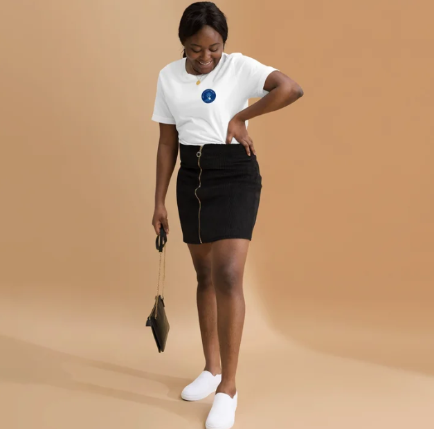 Woman wearing a white t-shirt with a Bleu Chocolàt logo and a black skirt on a beige background