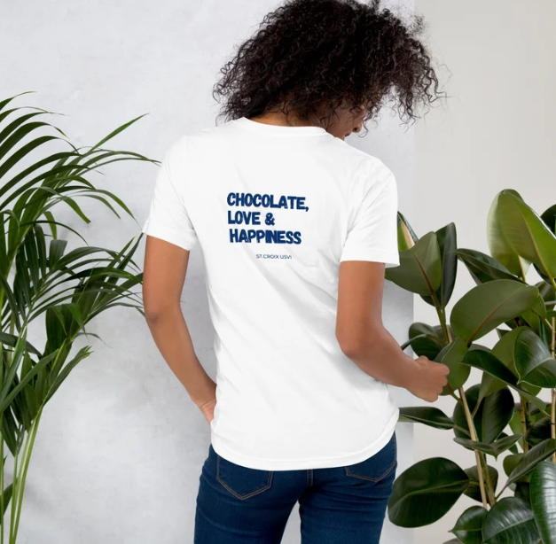 Person wearing a white t-shirt with 'Chocolate, Love & Happiness' text on the back, standing between two plants.