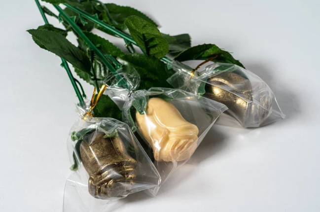 Bouquet of gold and beige chocolate roses in clear packaging on a white background