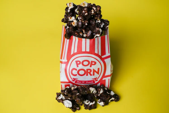 Popcorn container filled with chocolate-covered popcorn on a yellow background