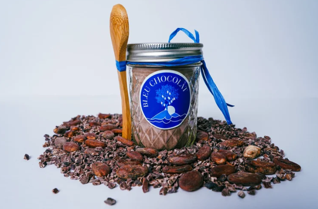 Jar of chocolate with a wooden spoon on a white background