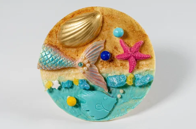 Decorative cookie with mermaid design, shell, and starfish on a white background