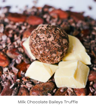 Milk chocolate Baileys truffle on a bed of chocolate shavings and white chocolate