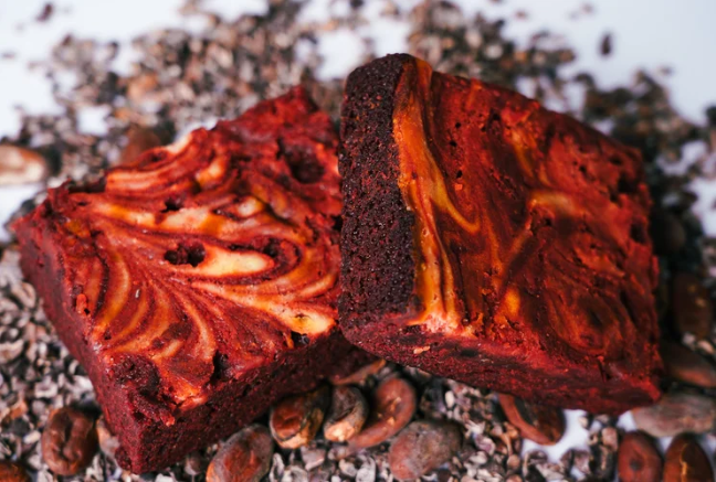 Two brownie squares with a marbled pattern on a surface with coffee beans.