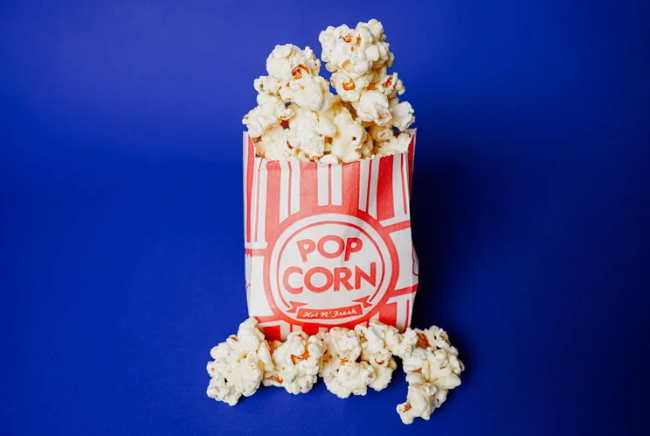 Popcorn in a red and white striped bucket on a blue background